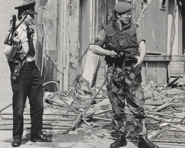 An RUC officer and Royal Military Policeman stand guard by a bombed building, 1979