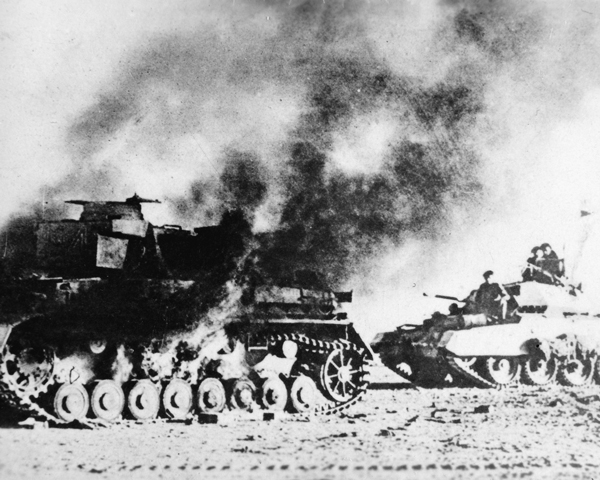 A British Crusader tank passes a burning German Panzer Mk IV, 1941