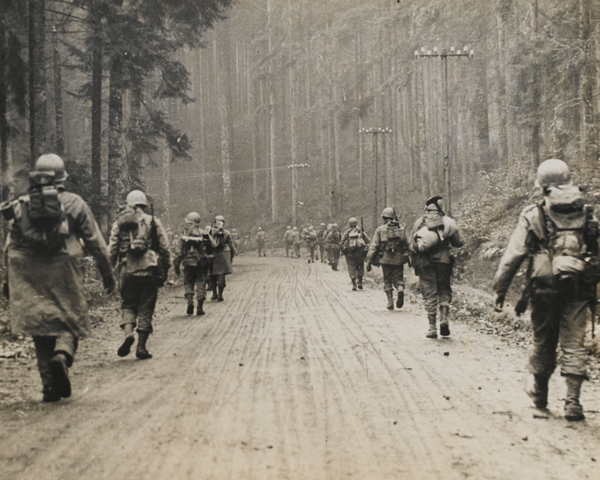 Infantry from the US 7th Army march through a forest, January 1945