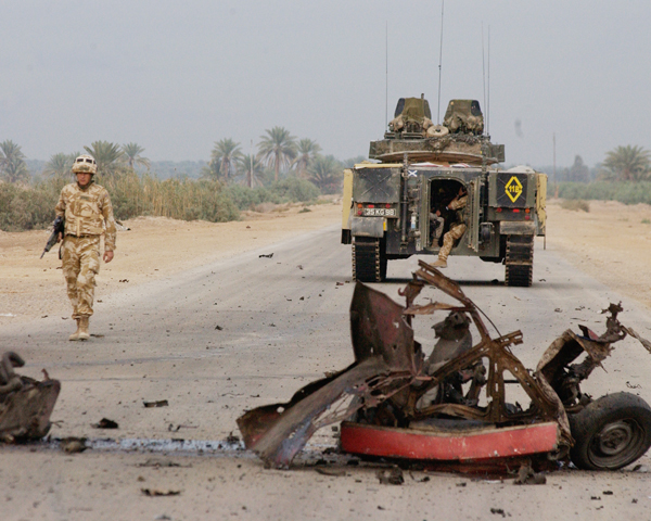 A British officer walks from his Warrior armoured vehicle to the scene of an insurgent car bomb, 2004