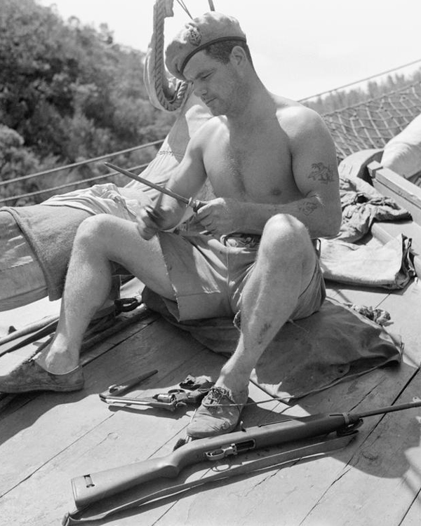 Corporal Aubrey, Special Boat Service, sharpens his fighting knife while preparing for a mission, 1945 