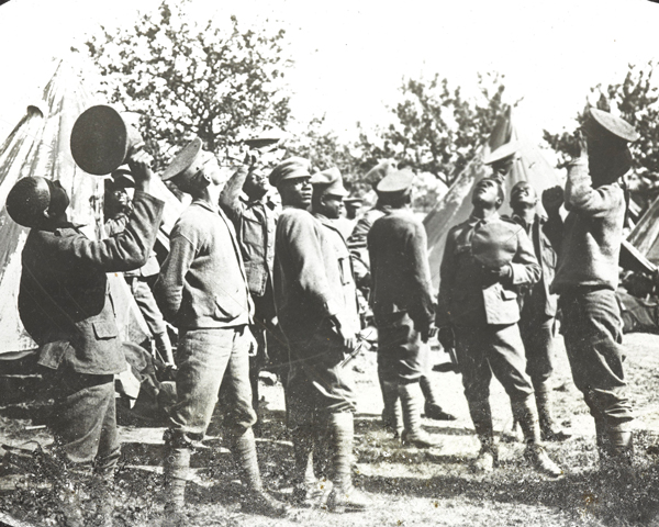 Members of the British West Indies Regiment observe aircraft above their camp on the Albert to Amiens Road, 1918