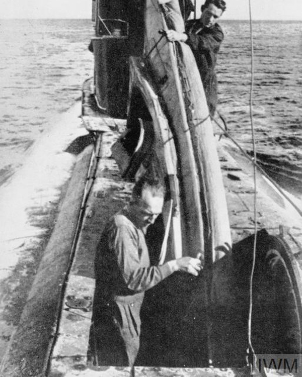 Robin Harbud and Sgt Cox manhandle their COPP canoe through the forward hatch of a submarine