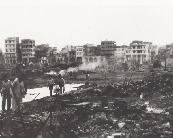 Egyptian civilians survey the burnt out ruins in Port Said, 1956 