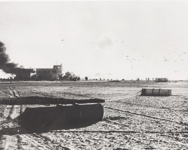 Equipment canisters litter El Gamil airfield as paratroopers land on the drop zone, 1956 