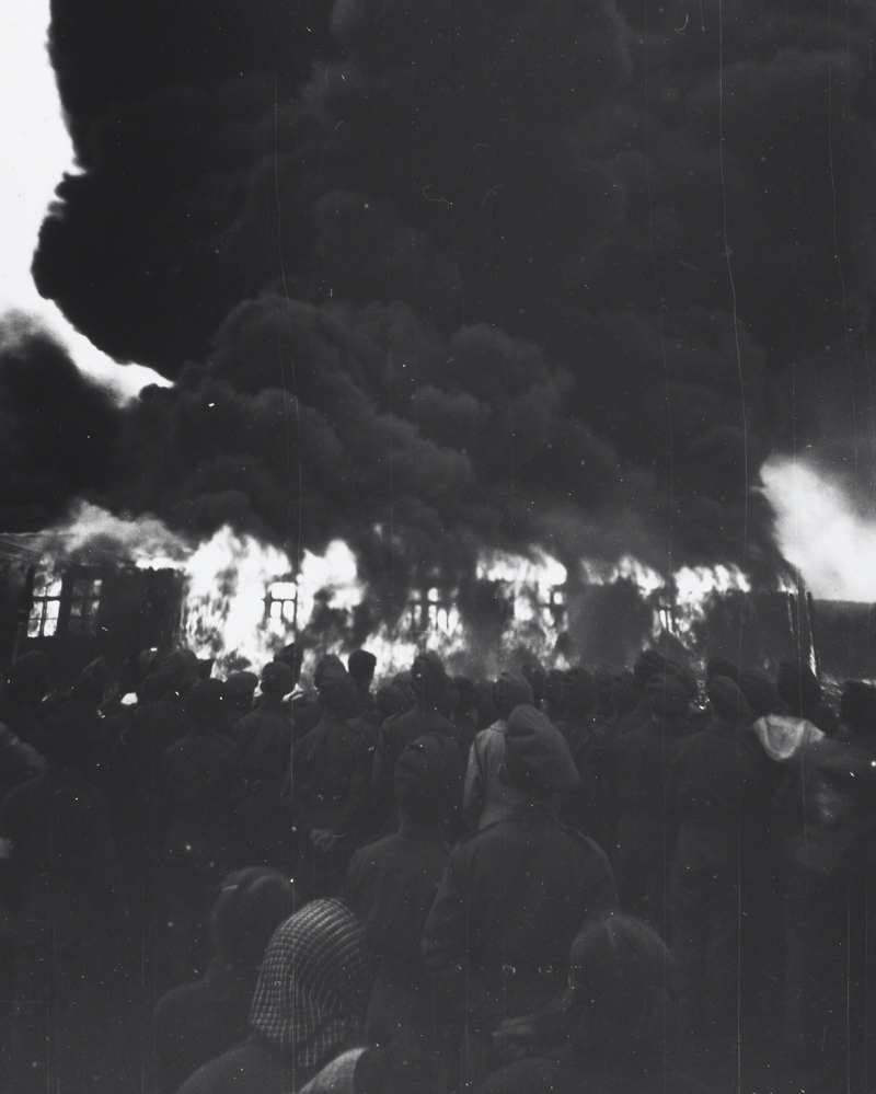 Soldiers and civilians watch the burning of Belsen, 21 May 1945