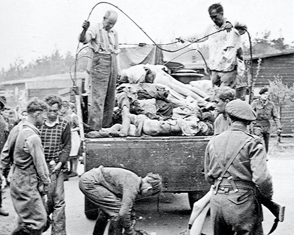 A British soldier guards SS members as they collect the dead at Belsen Concentration Camp following its liberation, April 1945