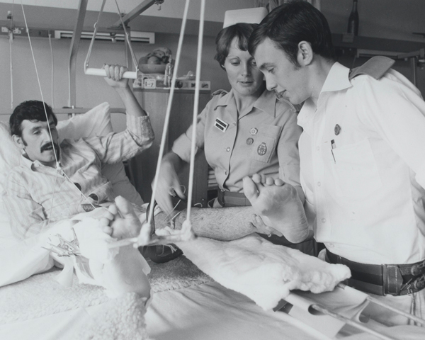 A QARANC nurse helps removes the plaster cast from a patient's leg, 1975