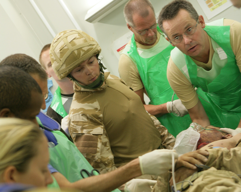 A MERT medic (in combat fatigues) oversees the handover of a casualty to the staff at Camp Bastion, 2007