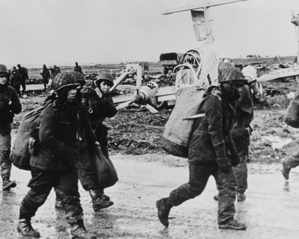 Argentine prisoners pass a wrecked Pucara aircraft, Goose Green, 1982