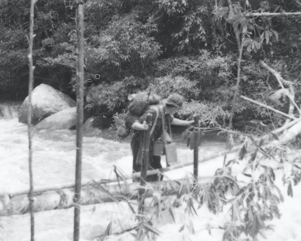 A members of the Coldstream Guards crossing a river in Malaya, c1948