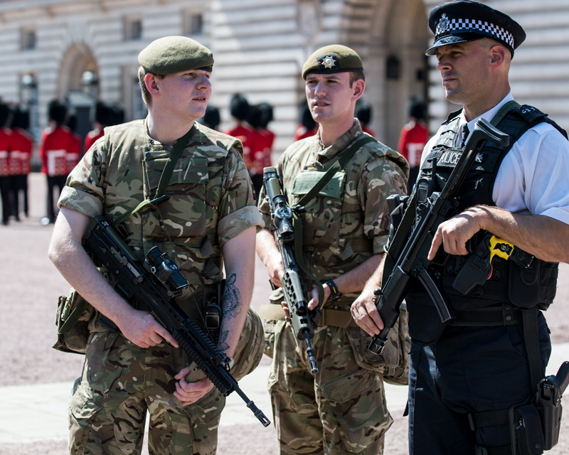 Coldstream Guardsmen with an armed police officer at Buckingham Palace during Operation Temperer, 2017