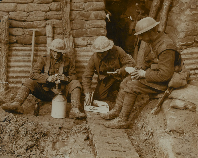 Soldiers with their rum ration in a trench, c1917