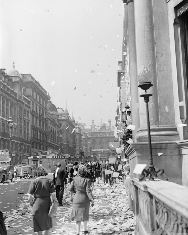 Civilians walk amongst piles of ticker tape on Lower Regent Street, London, to celebrate victory over Japan, 15 August 1945