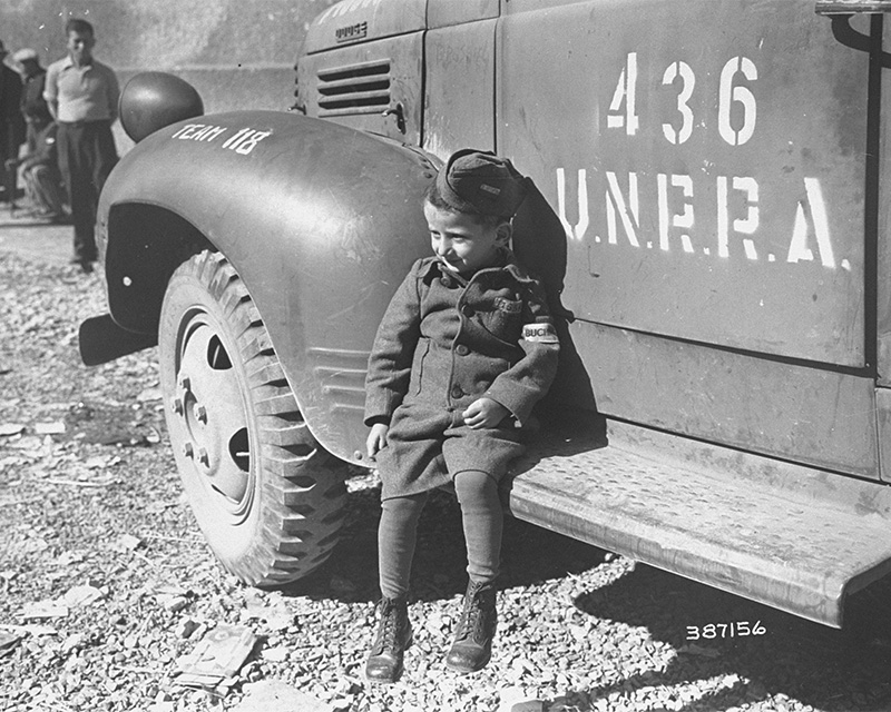 Joseph Schleifstein, a four-year-old survivor of Buchenwald, sits on the running board of an UNRRA truck soon after the liberation of the camp.