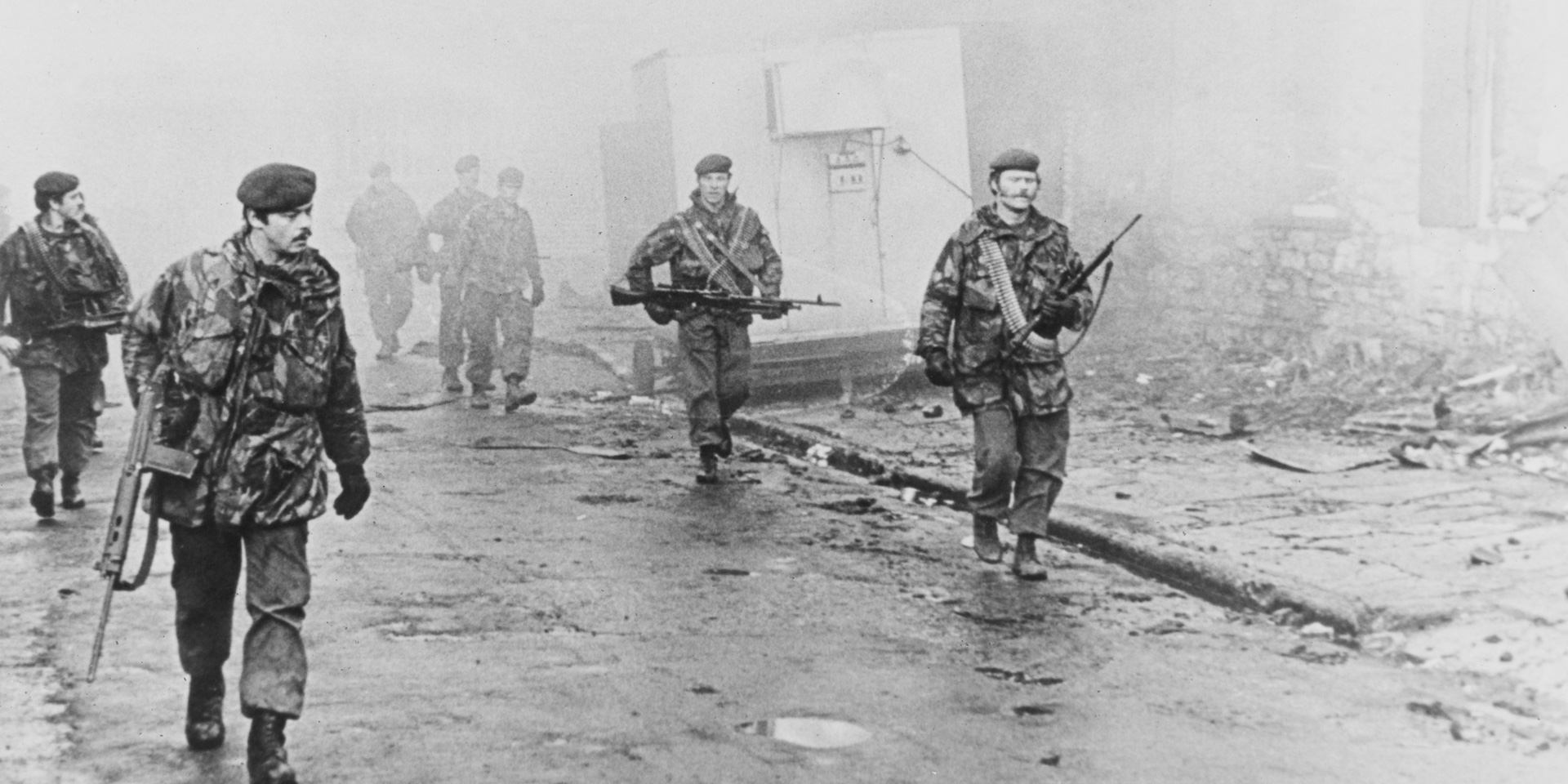 A view of a group of paras on foot patrol down a ruined street on the Falklands, 1982