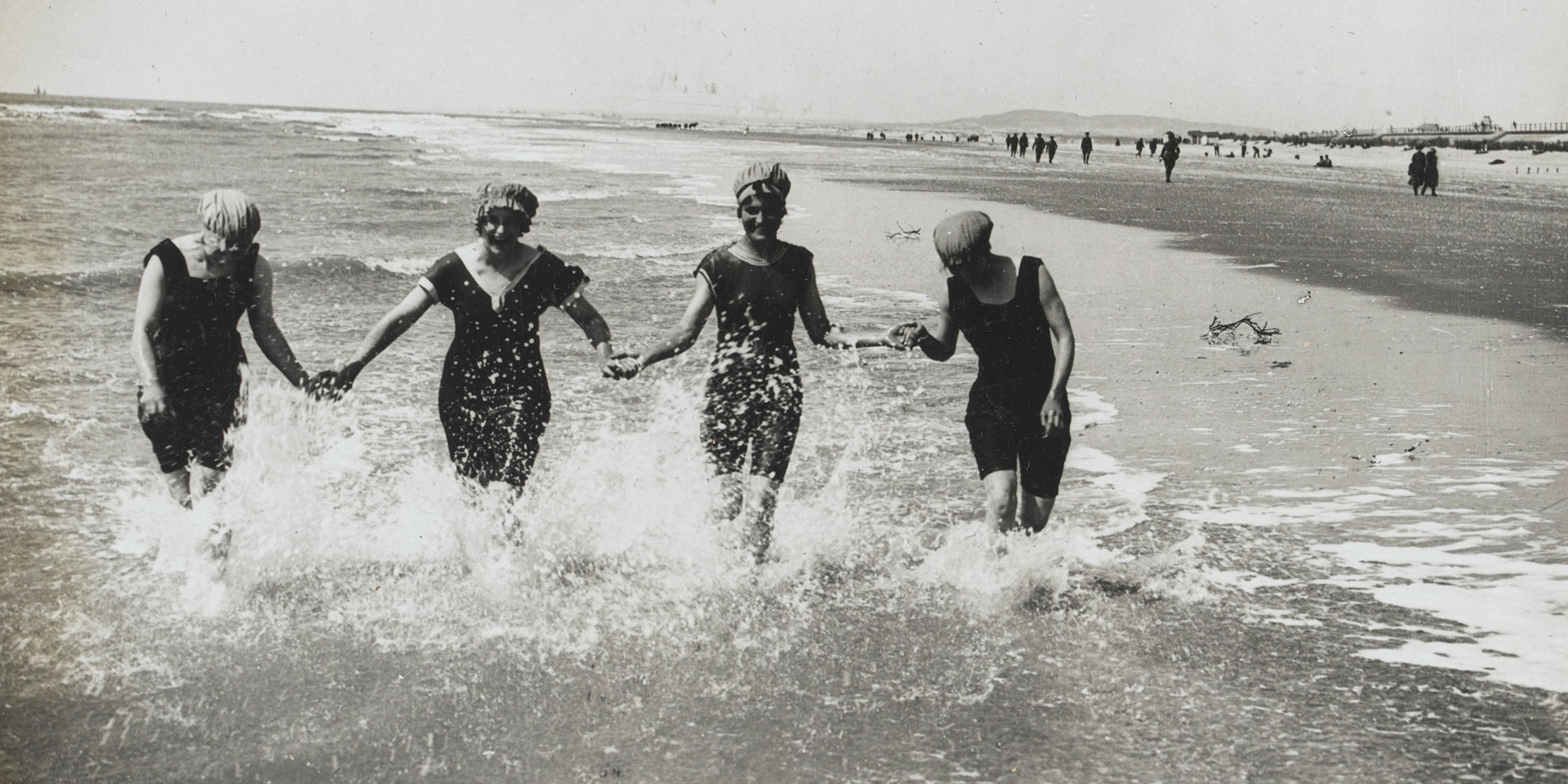 Photograph of four WAACs in bathing costumes, hand in hand in the sea.