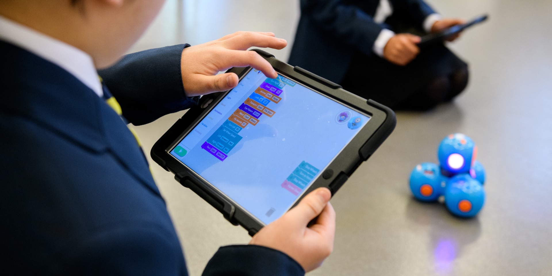 School boy using block coding to control a Dash robot