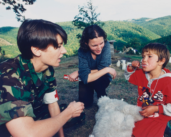 An Army dentist and interpreter with a local child, 1999