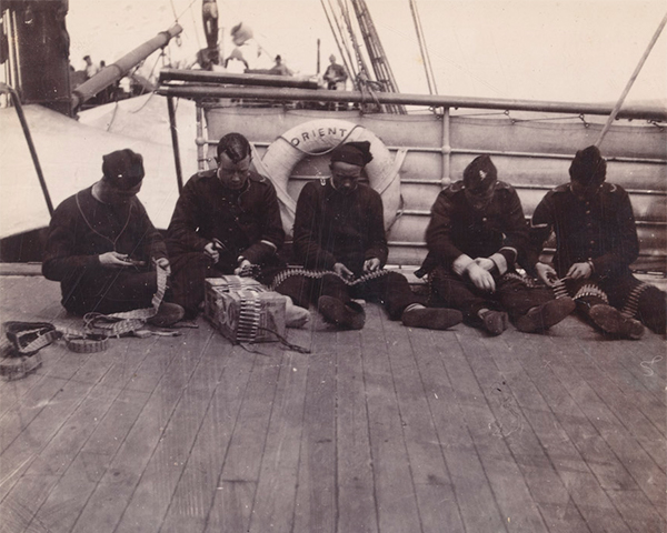 Men of the West Riding Regiment loading Maxim machine gun belts, en route to South Africa, 1900