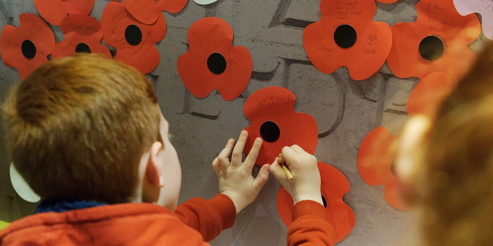 Child writing a message on paper poppies