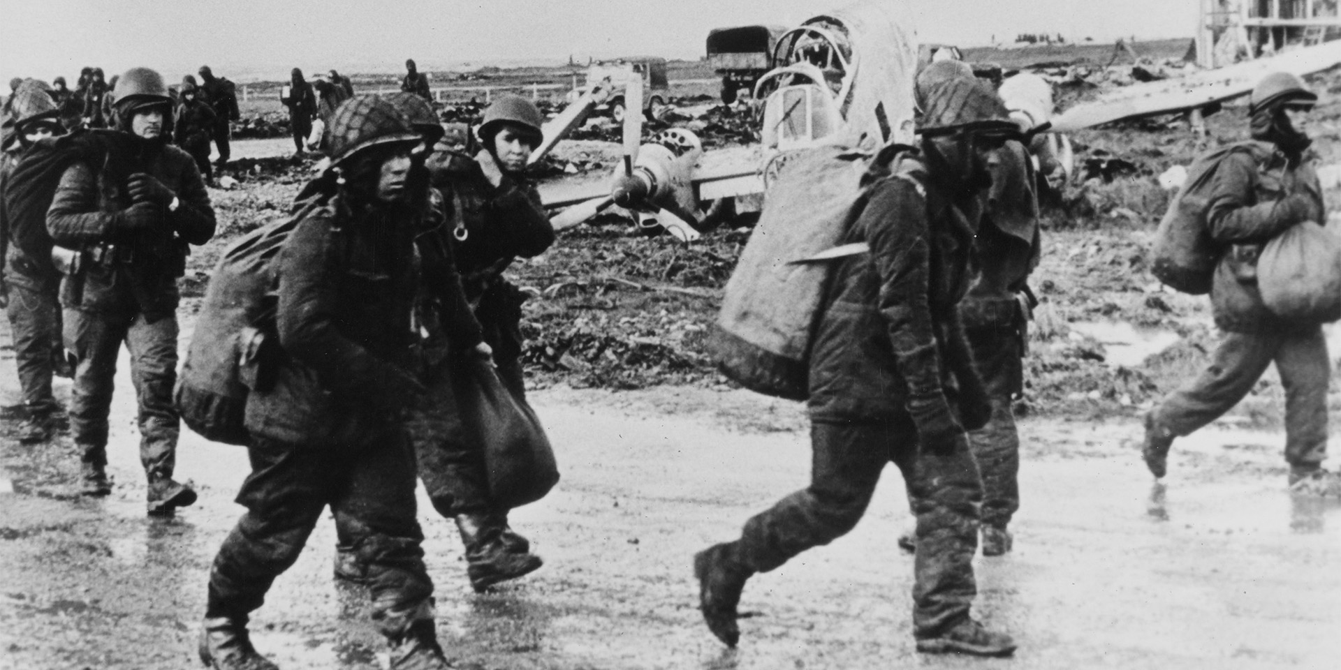 Argentine prisoners pass wrecked aircraft, Goose Green, 1982