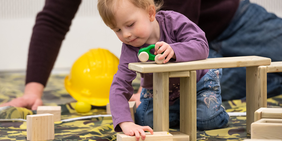 Toddler playing with toy car and building blocks