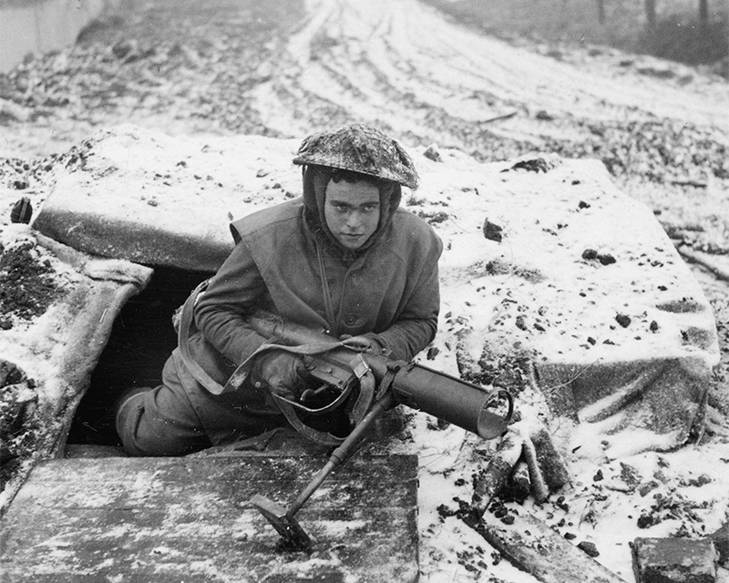 A member of 1st Battalion, The Rifle Brigade, leaving a dug-out in the village of Niewstadt, Netherlands, 28 December 1944