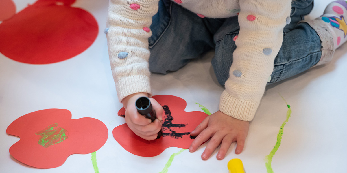 Child decorating a paper poppy