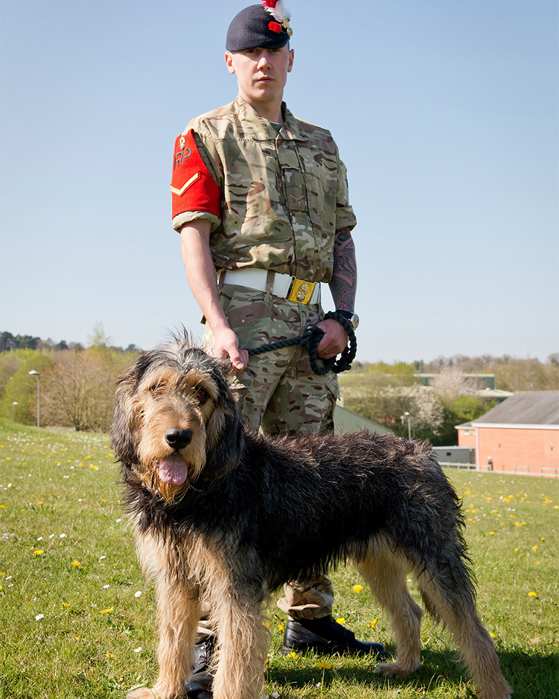 A lance corporal of The Royal Regiment of Fusiliers with the unit's 'stand-in' mascot, 'George' the Otterhound, 2015