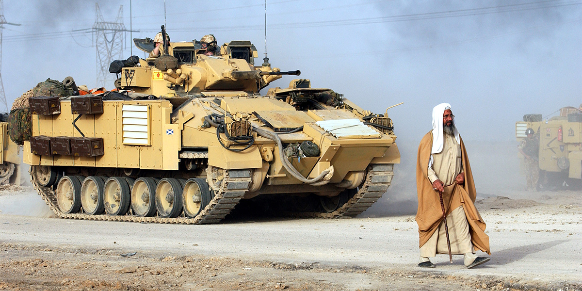 A civilian walks in front of a Warrior Infantry Fighting Vehicle, Iraq, 2003