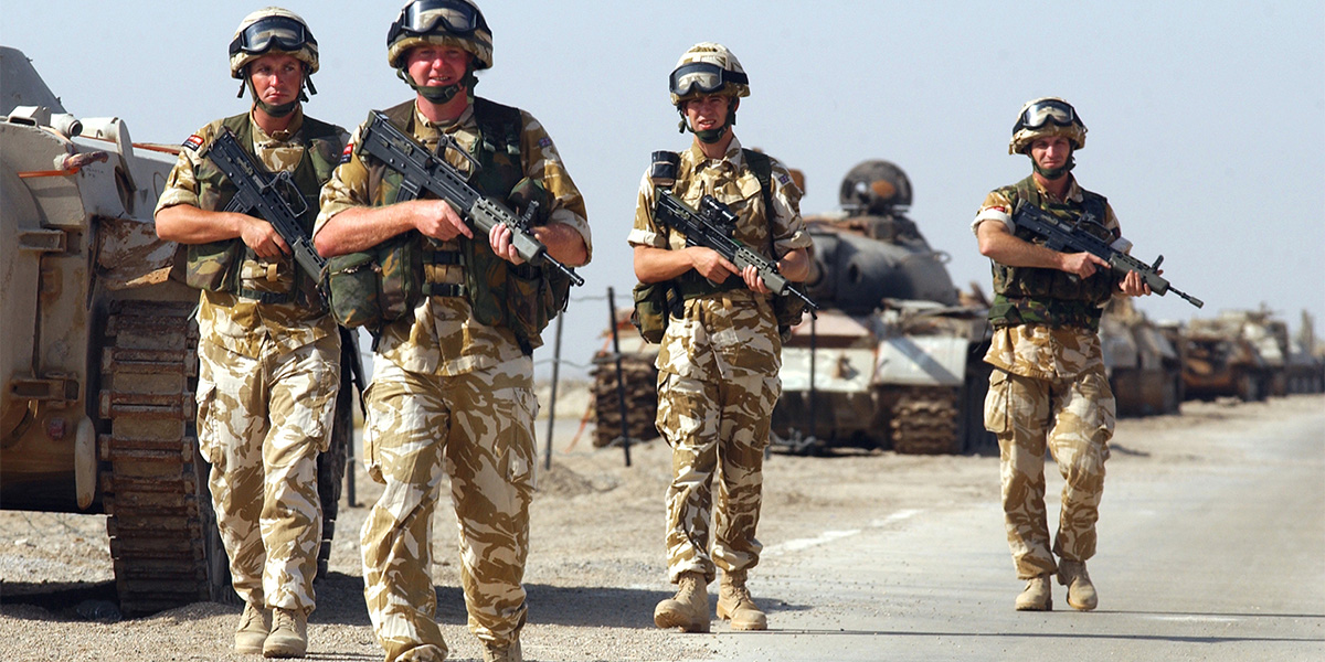 British troops advance past knocked-out and abandoned Iraqi tanks, 2003