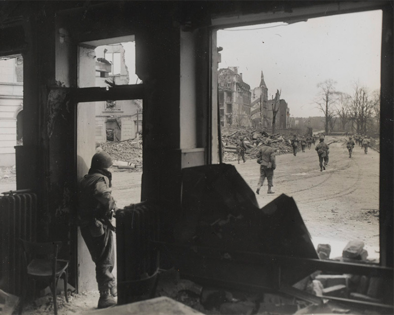 An American patrol advances towards the centre of a war-torn German town, 1945