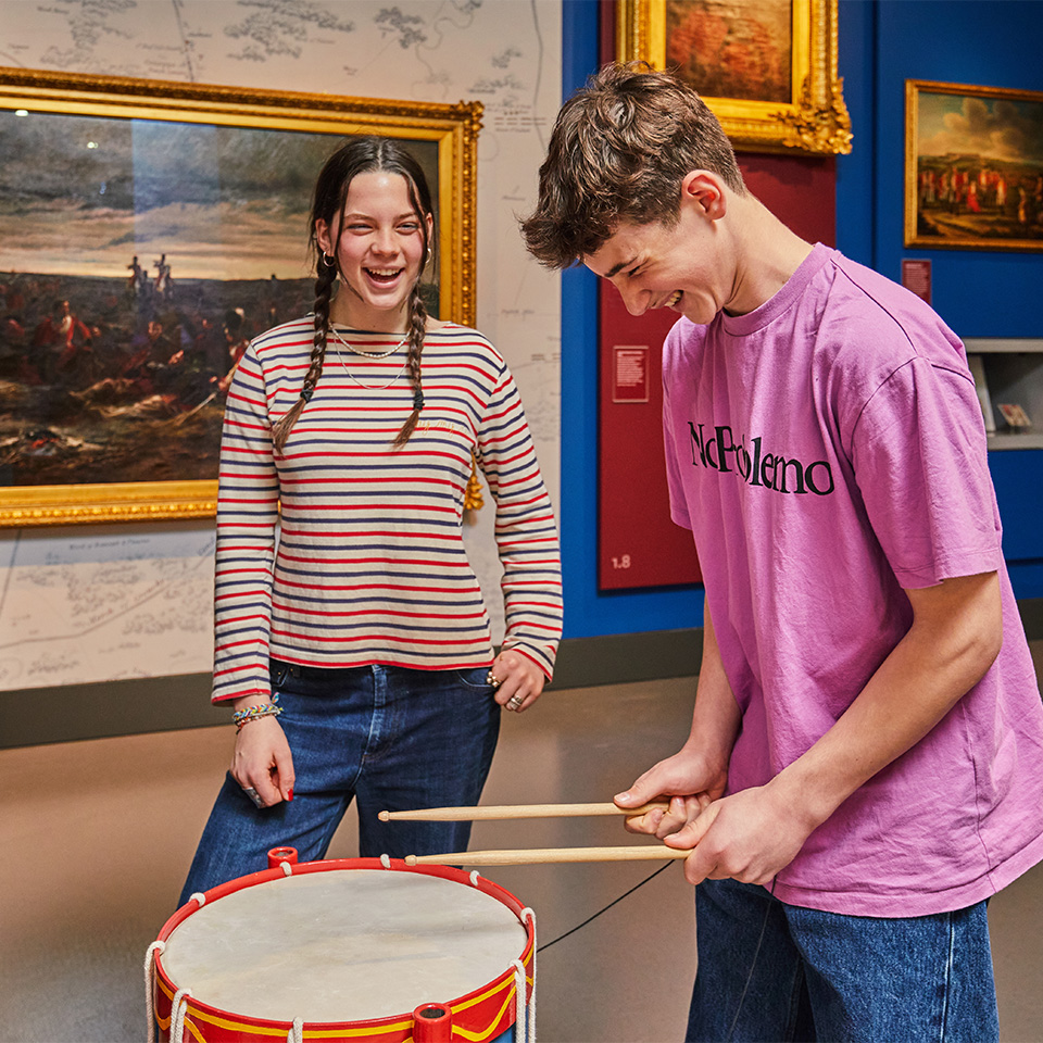 Visitor having a go on the battle drum in the Conflict in Europe gallery