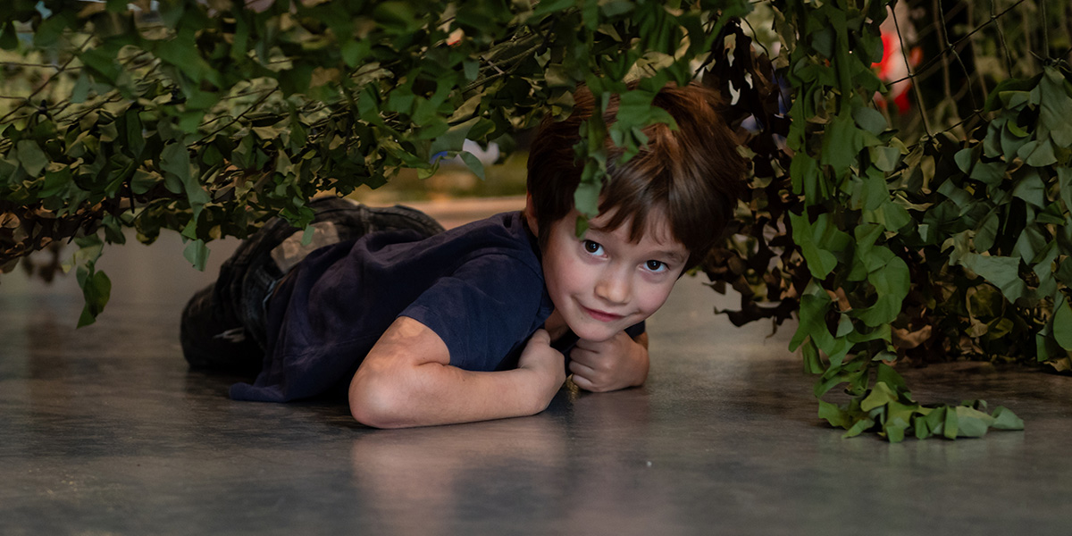 Child crawling under a scramble net