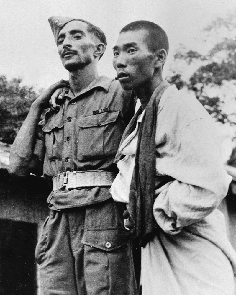 An Indian Army medic helping a wounded Japanese prisoner of war, 1945