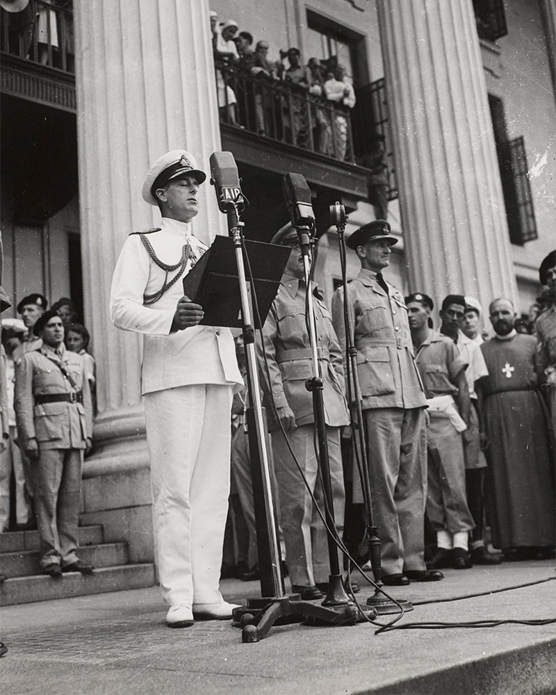 Lord Louis Mountbatten, Supreme Allied Commander Southeast Asia, reads the Order of the Day from the steps of the Municipal Building in Singapore, 12 September 1945