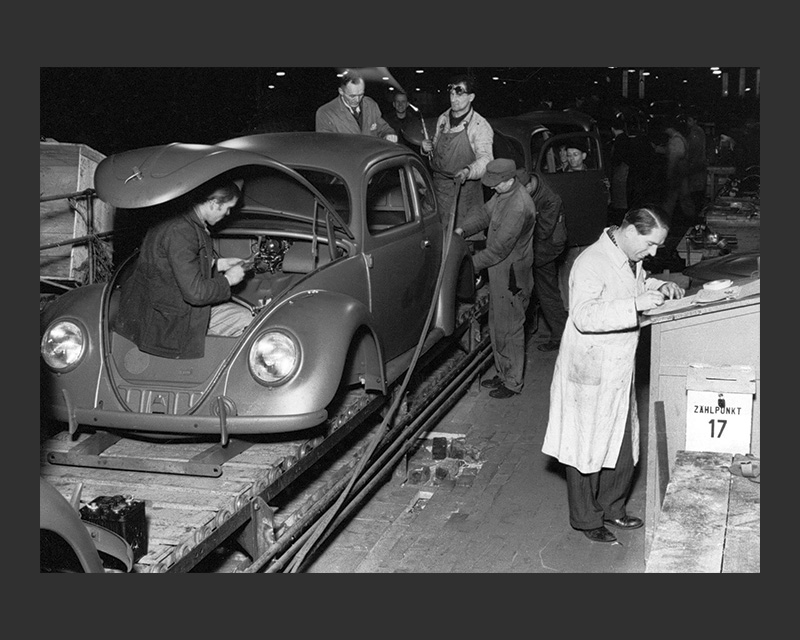 Men building Volkswagen Beetles in an assembly line