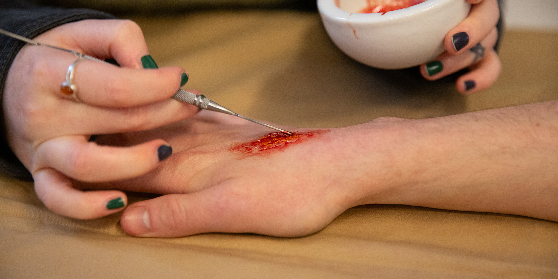 A fake wound being painted on to a visitor's hand
