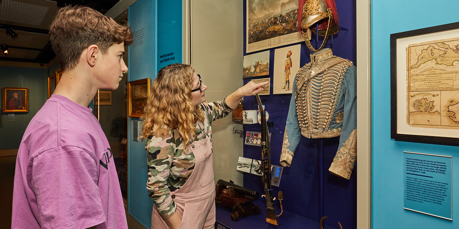 Visitors examining a display of art and objects in the Global Role gallery at the National Army Museum