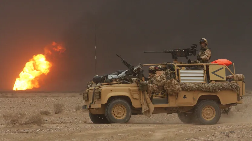 A Royal Irish Regiment vehicle passes a burning oil well during the invasion of Iraq, March 2003