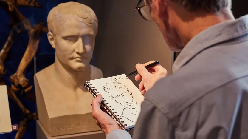 A museum visitor sketching a bust of Napoleon on display in a gallery