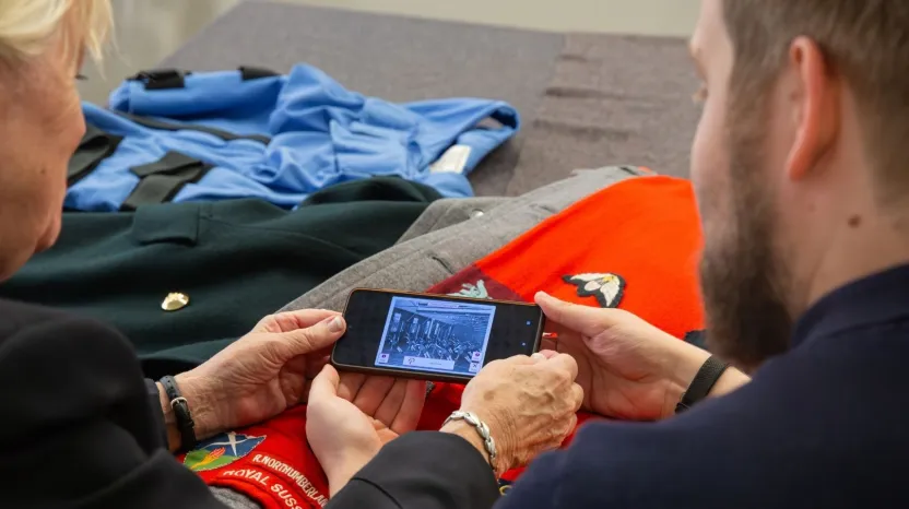 A man and woman look at a smartphone.