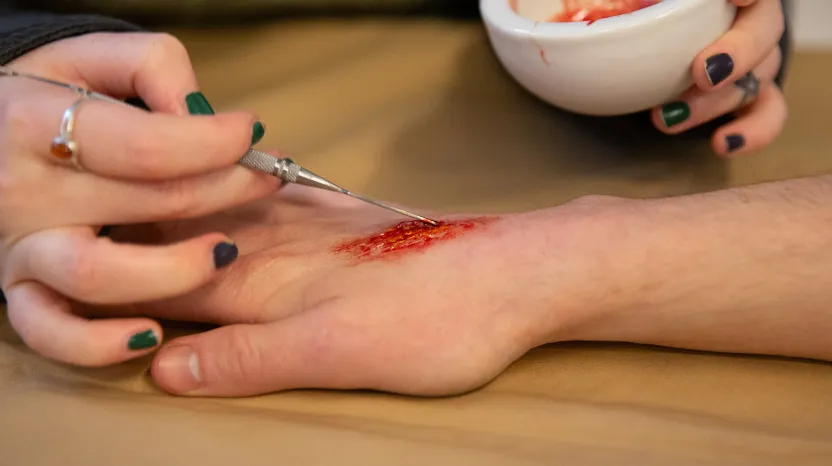 A fake wound being painted on to a visitor's hand
