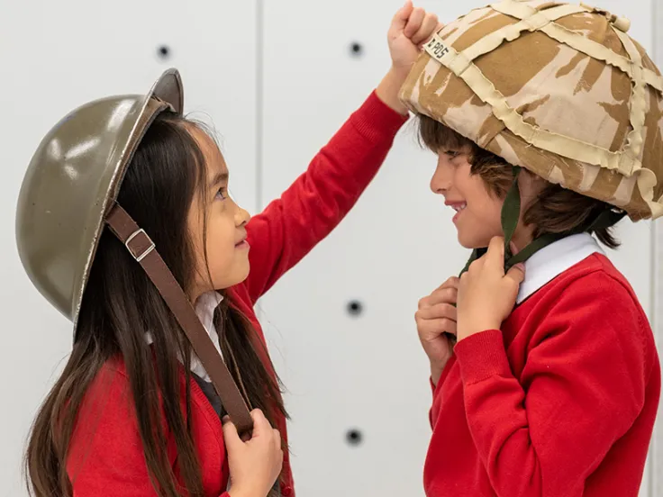 School children trying on different Army helmets