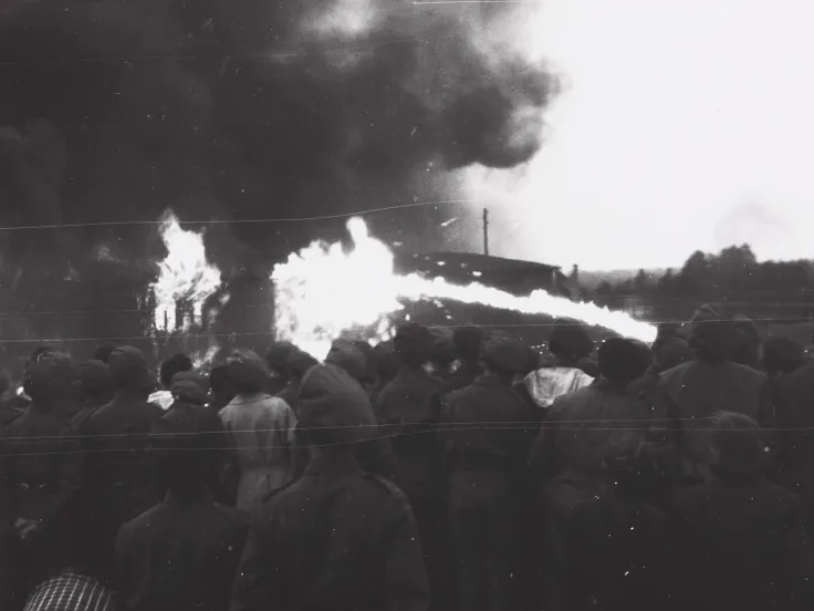 A crowd watching the Bergen-Belsen concentration camp burn down