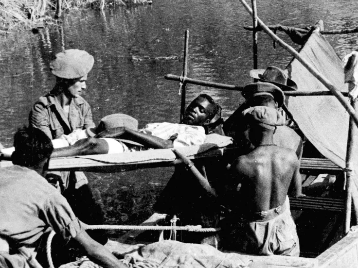 A wounded African soldier being carried by stretcher bearers on to a motor launch, Burma, c1944