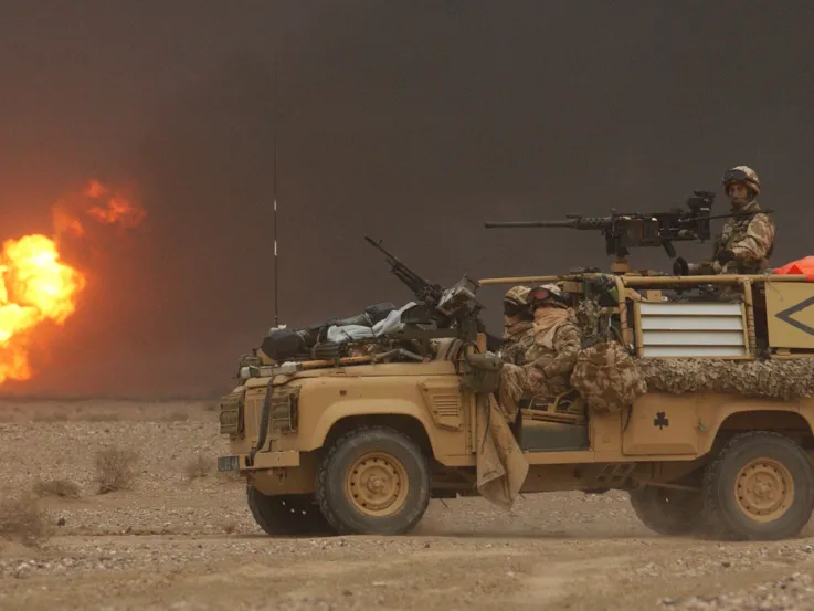 A Royal Irish Regiment vehicle passes a burning oil well during the invasion of Iraq, March 2003