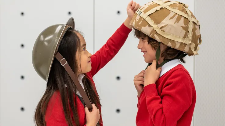 School children trying on different Army helmets