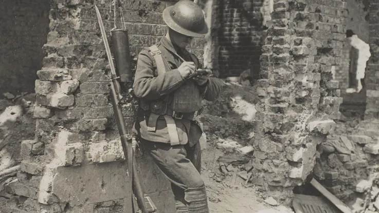 A soldier writing home while leaning against a ruined wall, Liévin, c1917